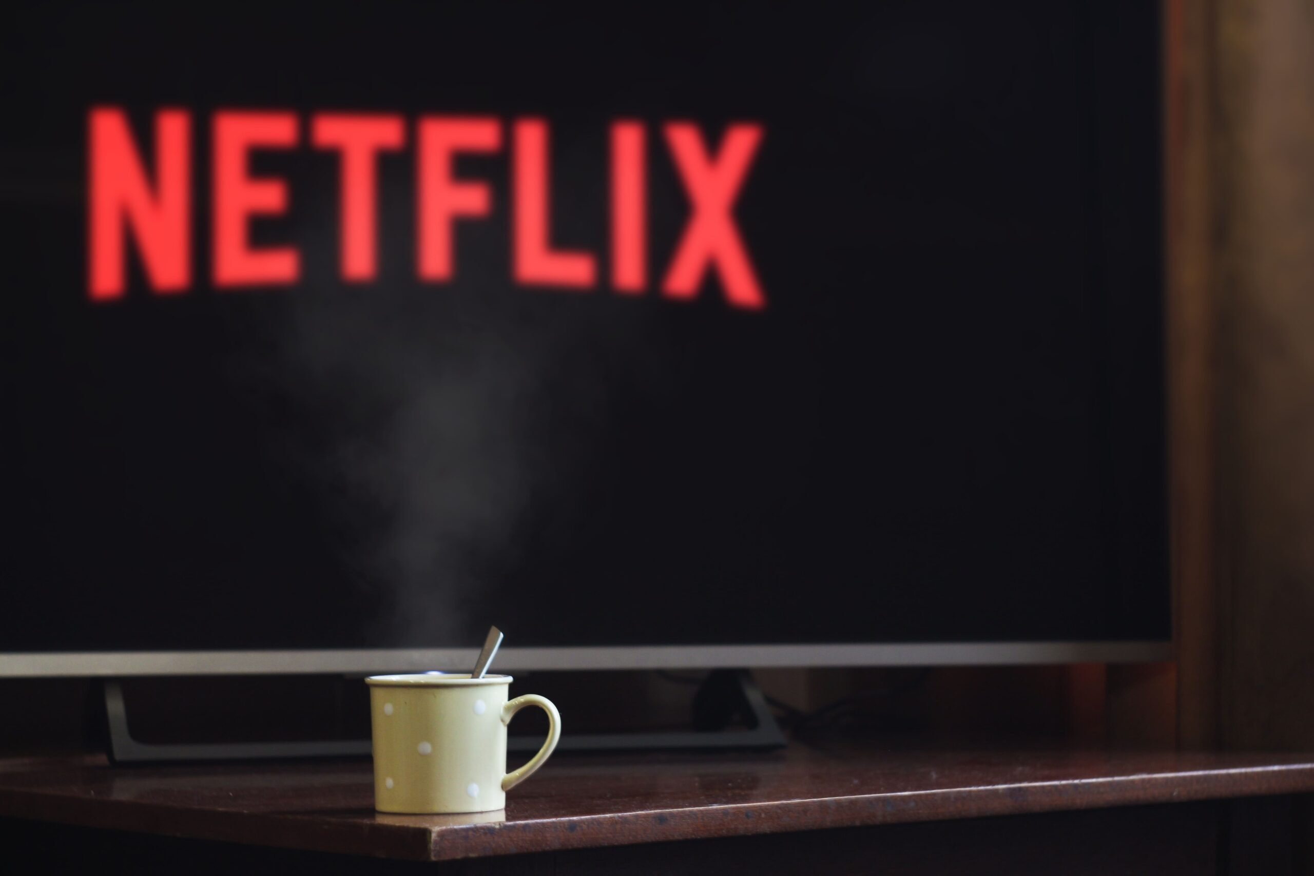 Netflix loading screen on television with a cup of coffee in front.